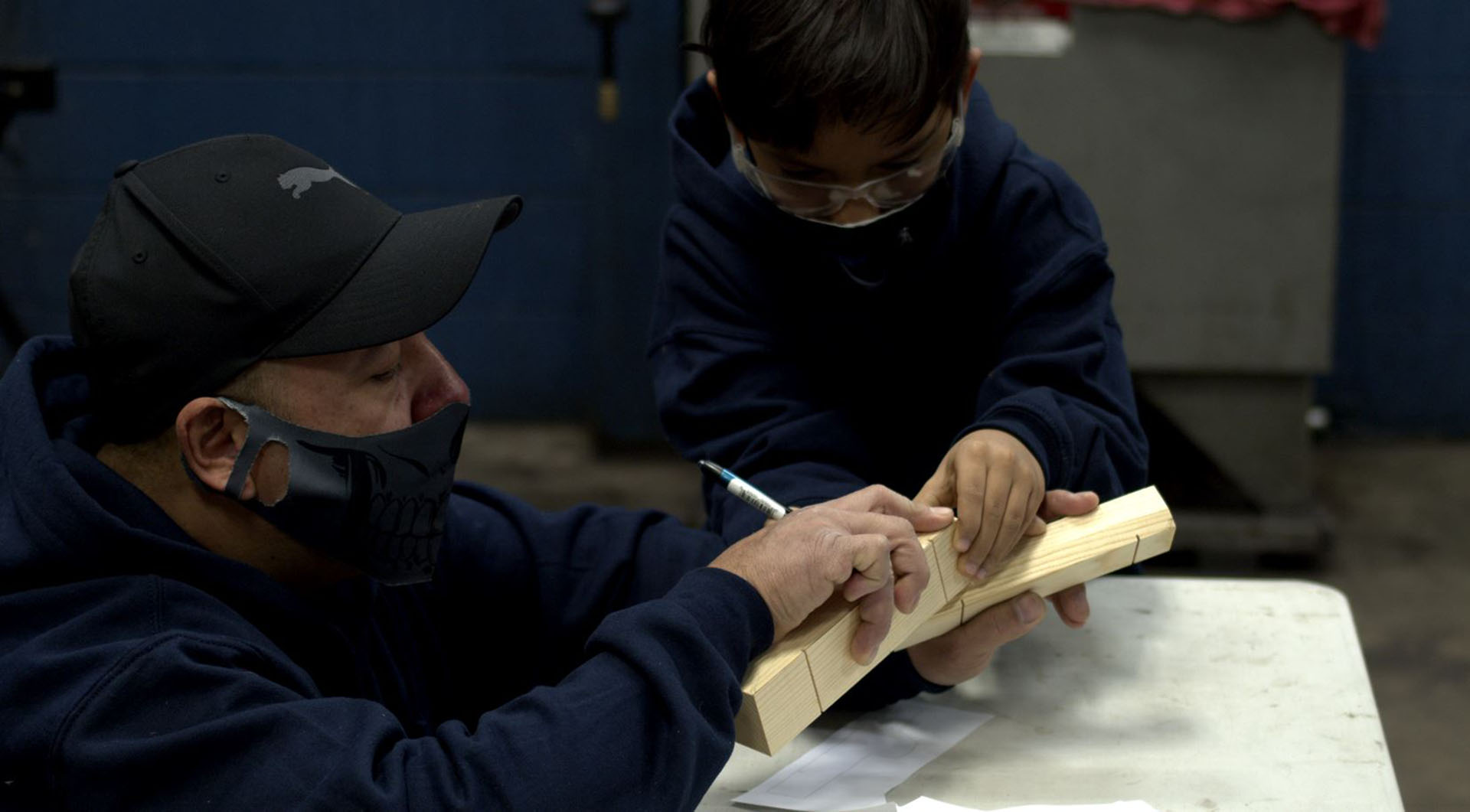 An adult and child participating in a Pinewood Derby workshop.